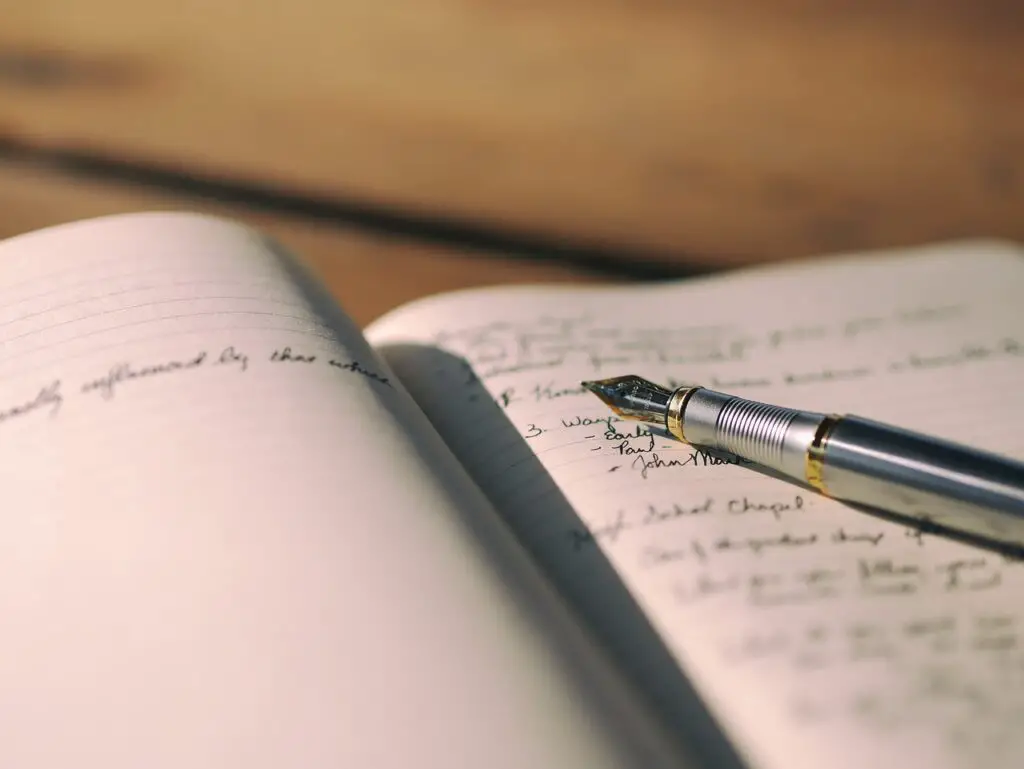 fountain pen resting on the page of a filled out handwritten notebook