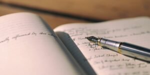 fountain pen resting on the page of a filled out handwritten notebook