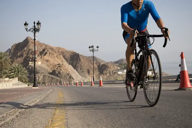 man riding a racing bicycle on the road next to a line of traffic cones